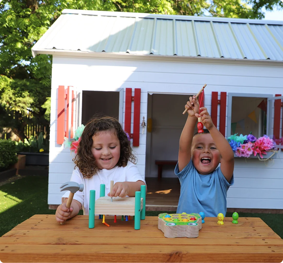 Children playing with Rivelle activities in front of the Kids Kottage outdoor learning space.